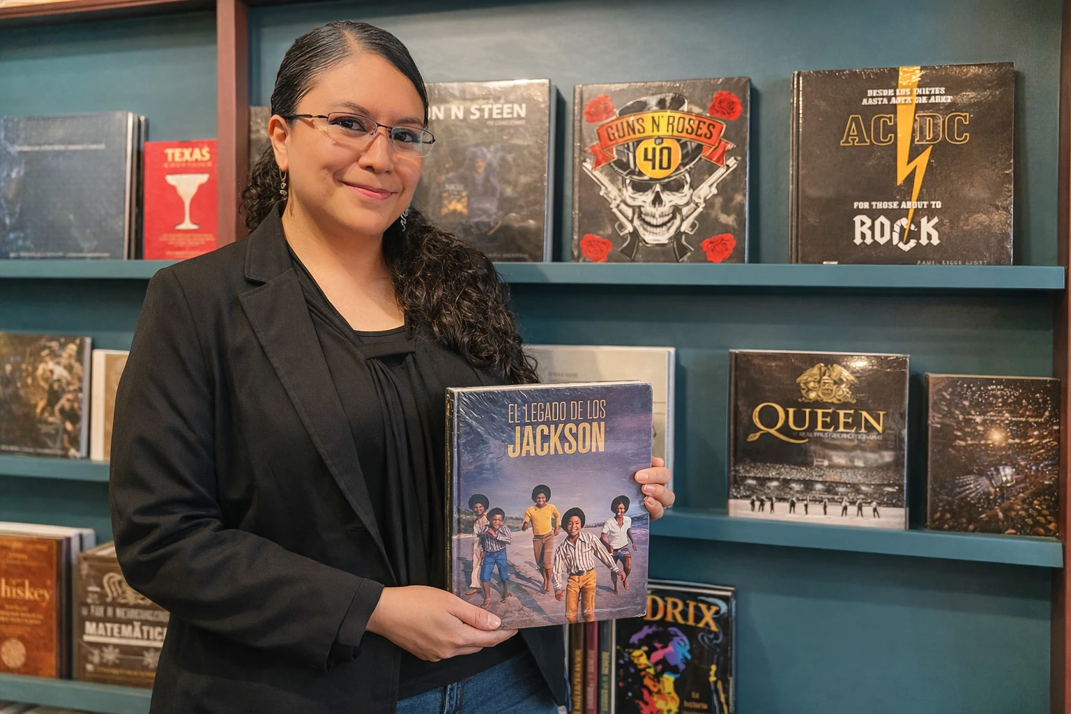 Tania sosteniendo el libro El legado de los Jackson frente a una estantería llena de libros de música